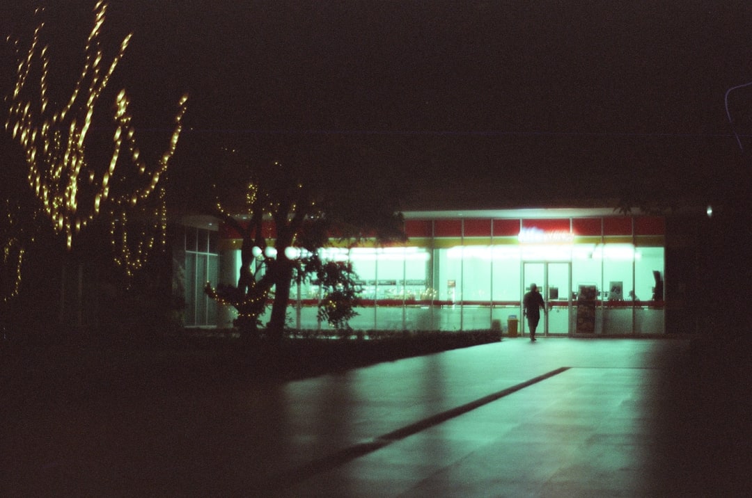 Illuminated Glass Building Through Night Trees. Shot with Olympus OM-1, Olympus Zuiko 50mm f/1.8, Cartenz 200 film